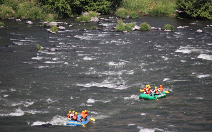 From an aerial point of view, two rafts containing people float along a river